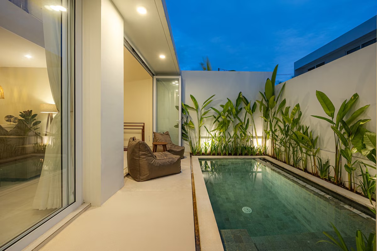 Pool at dusk with the living room lit behind it