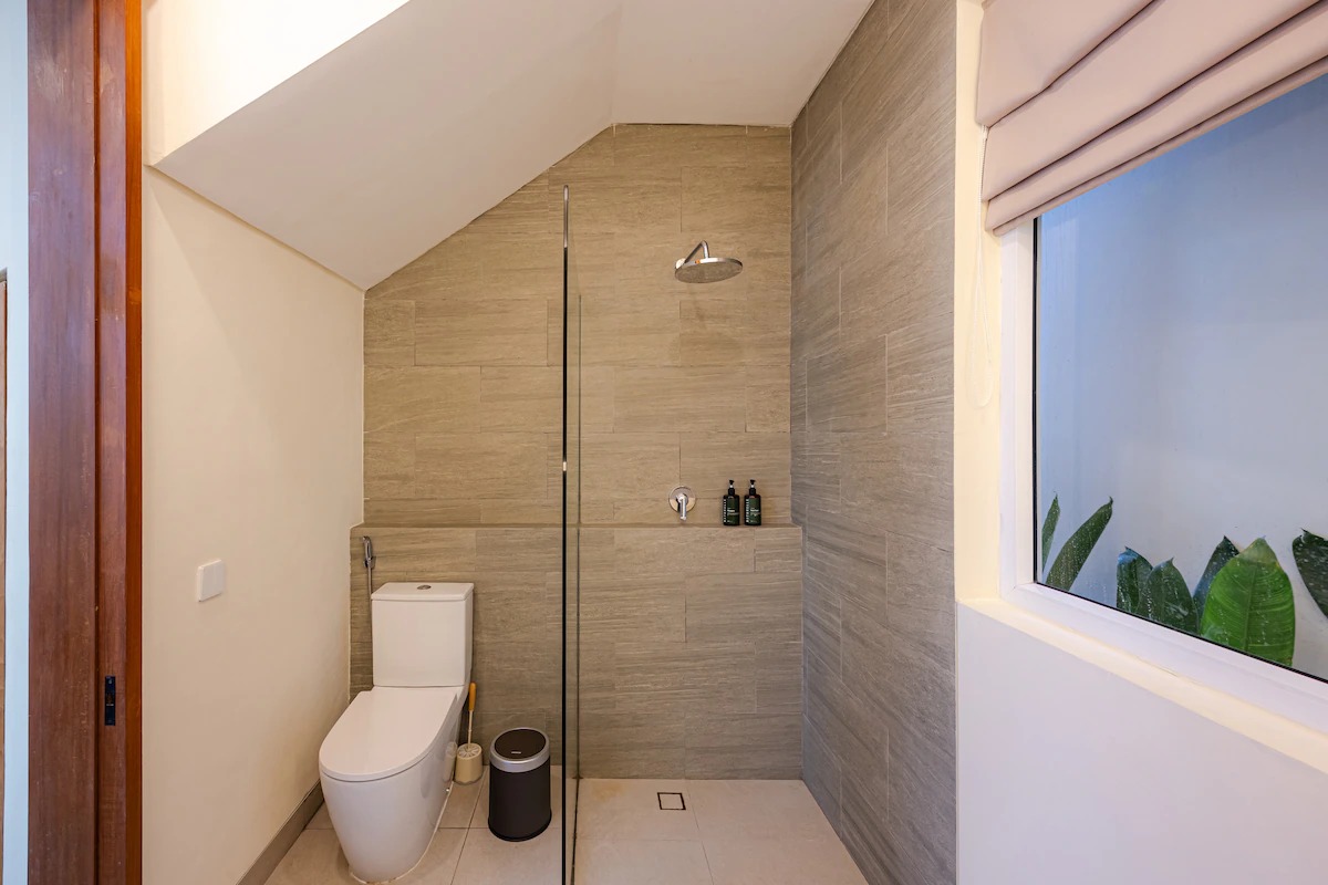 Bathroom shower and toilet under the sloped mezzanine ceiling