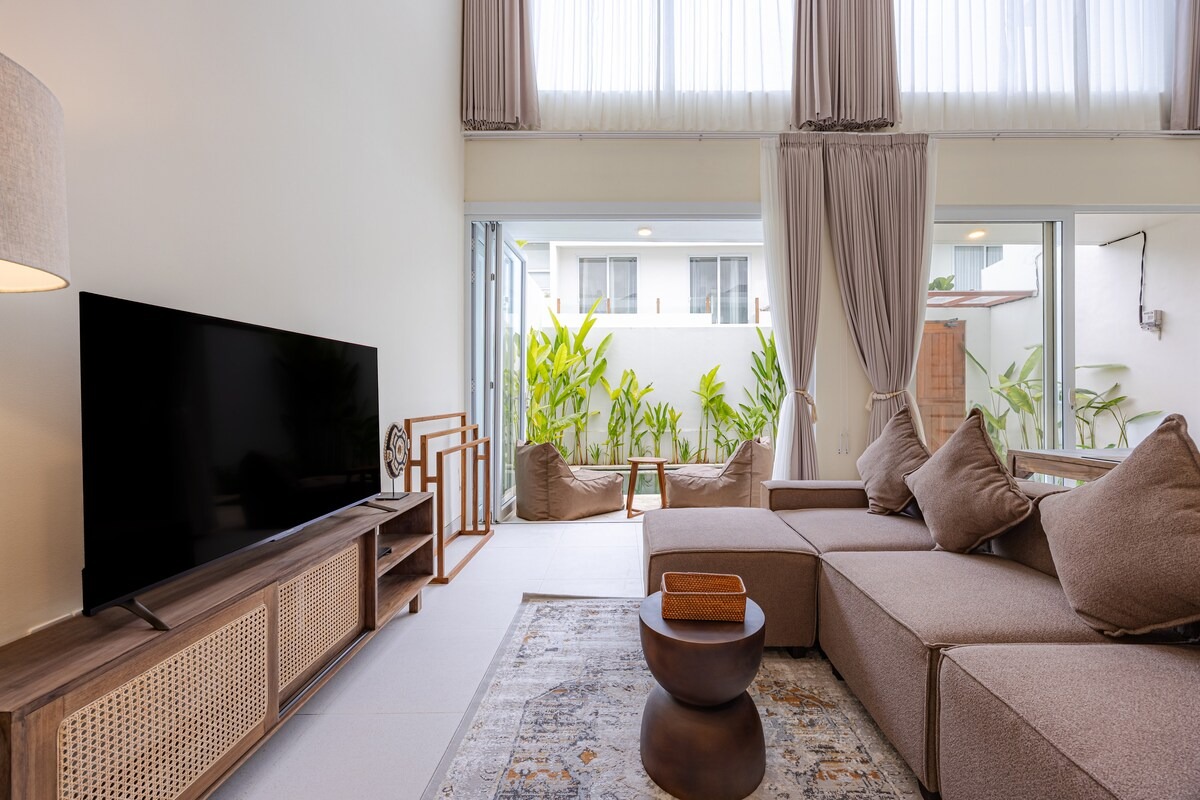 Living room sofa facing the TV, doors open to the pool